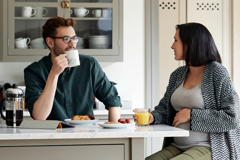A woman and man having coffee at their kitchen table